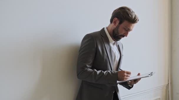 Concentrated Handsome Bearded Businessman Holding Clipboard Checking Something While Standing — 비디오