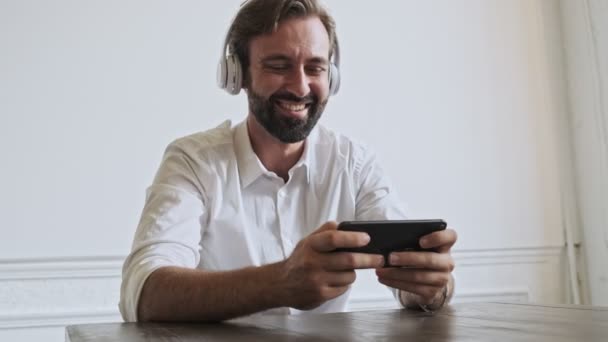 Veselý Pohledný Vousatý Podnikatel Poslouchá Hudbu Hraje Smartphone Zatímco Sedí — Stock video