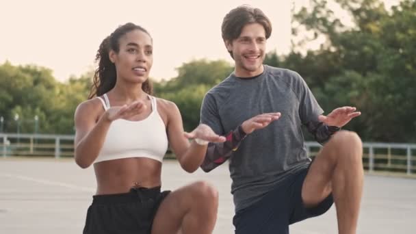 Desportivo Jovem Casal Sportswear Fazendo Exercício Suas Pernas Sorrindo Enquanto — Vídeo de Stock