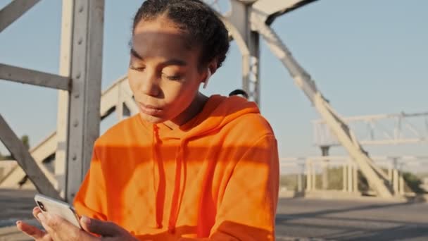 Hermosa Mujer Afroamericana Pacífica Con Capucha Naranja Usando Teléfono Inteligente — Vídeos de Stock