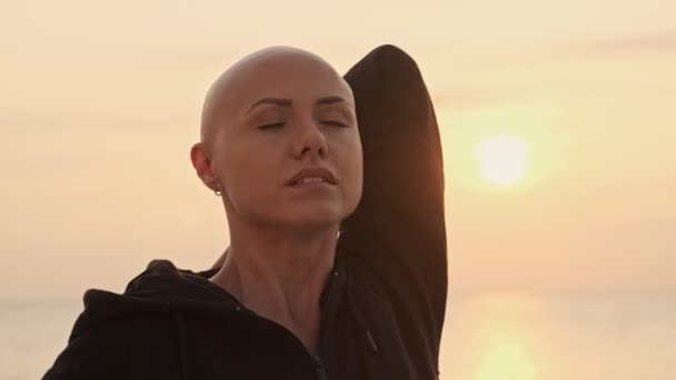 Concentrated Attractive Bald Sports Woman Stretching Hands Closed Eyes Sea — 비디오