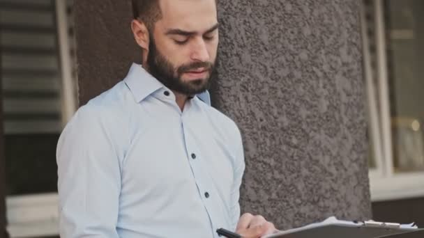 Серьезный Бородатый Бизнесмен Проверяет Читает Блокноте Улице — стоковое видео