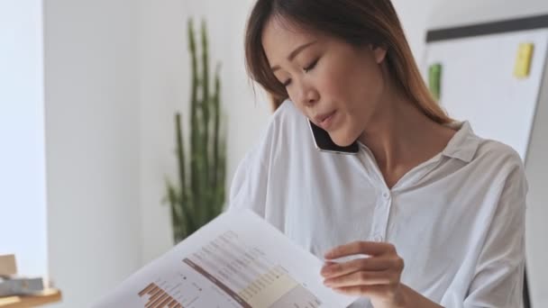 Hermosa Mujer Negocios Asiática Positiva Viendo Documentos Mientras Tiene Una — Vídeos de Stock