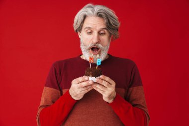 Doğum günü pastasında mumları söndüren yaşlı bir adamın portresi.