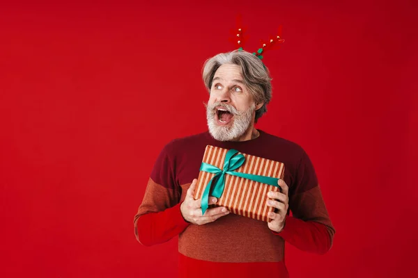 Porträt eines grauhaarigen alten Mannes im Pullover mit Weihnachtsgeschenk — Stockfoto