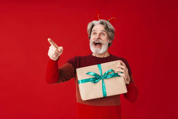 Porträt eines grauhaarigen alten Mannes im Pullover mit Weihnachtsgeschenk — Stockfoto