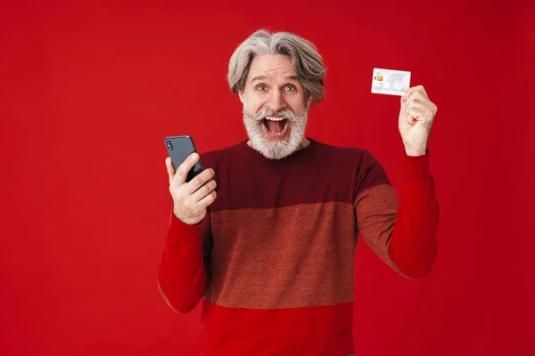 Portrait of gray-haired old man holding smartphone and credit ca — 스톡 사진