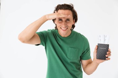 Pasaport ve seyahat biletleri taşıyan esmer bir genç adam resmi.