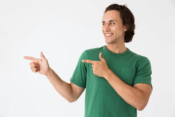 Beeld van optimistische jongeman in basic t-shirt lachend en wijzend vingers opzij — Stockfoto