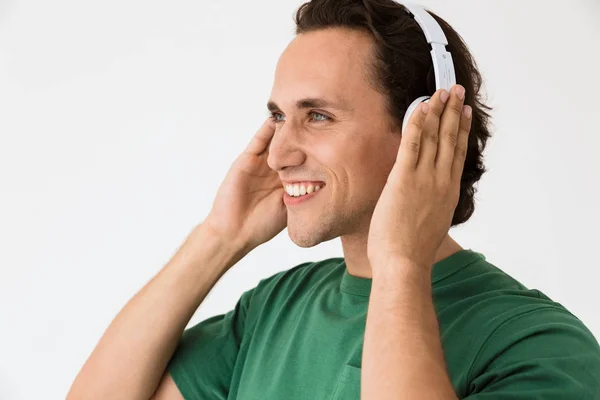 Image of pleased brunette man listening to music with headphones — 스톡 사진