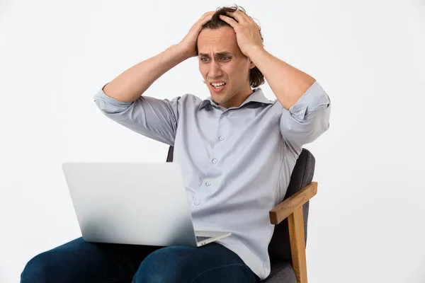 Imagen del hombre de negocios nervioso usando el ordenador portátil mientras está sentado en el brazo —  Fotos de Stock