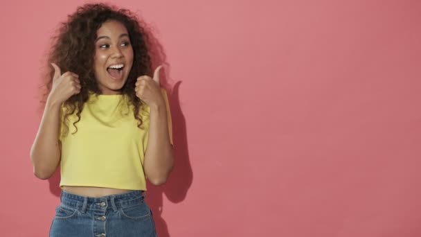 Joyful Pretty Curly Woman Showing Thumbs Looking Camera Pink Background — 비디오