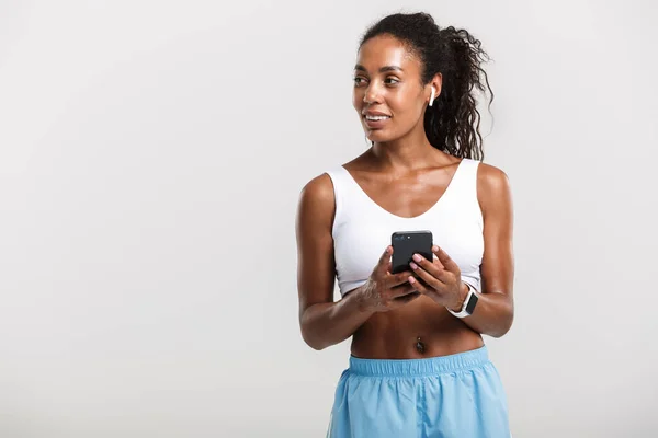 Portret van Afro-Amerikaanse vrouw met behulp van mobiele telefoon en oordoppen — Stockfoto