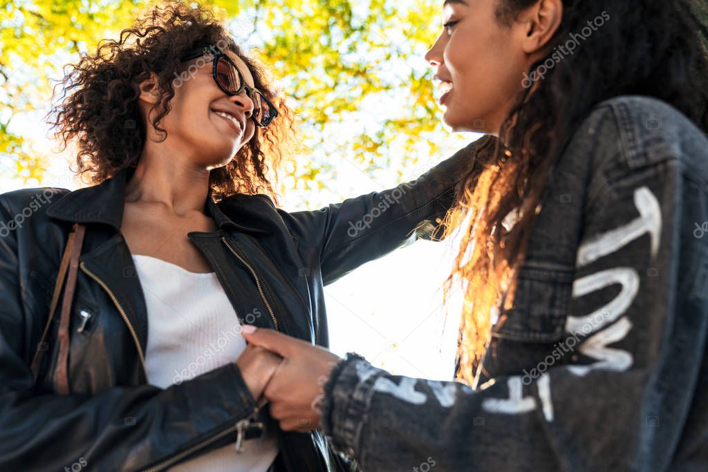 Image of american gay girls holding hands together by tree in pa