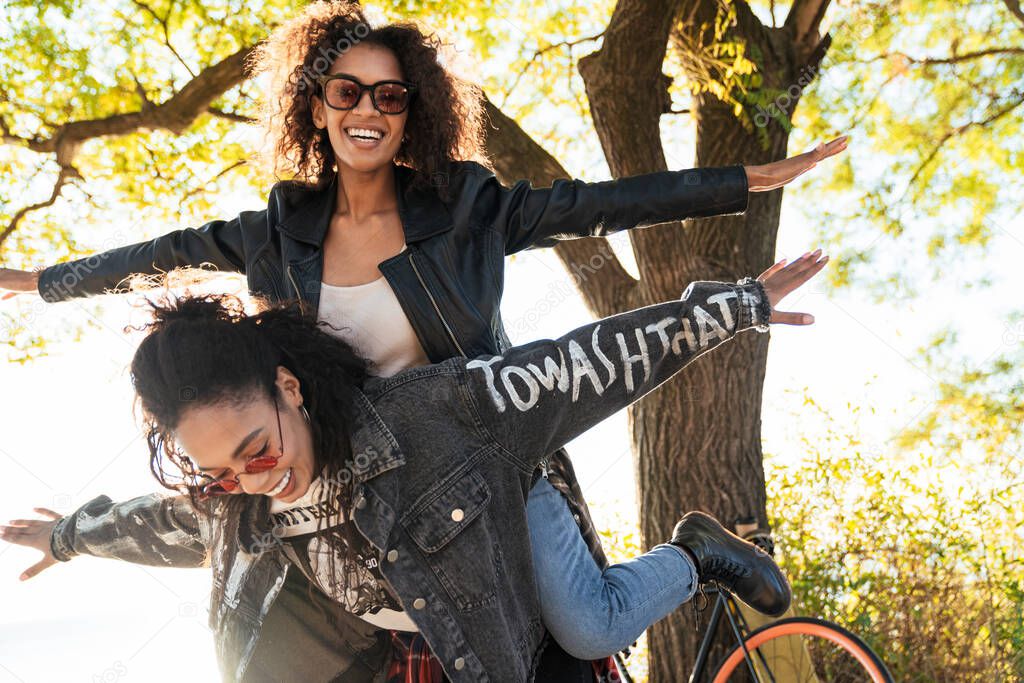 Image of two african american girls giving piggyback ride in par