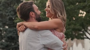 Sevimli genç çift yazın şehir caddesinde yürürken sarılıp öpüşüyorlar.
