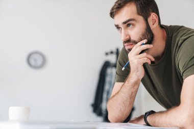 Belgeleri okuyup notlar alan odaklanmış beyaz bir adam resmi