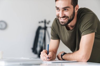 Genç gülümseyen beyaz adamın resmi. Belgeleri okuyor ve notlar alıyor.