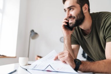 Belgeleri okuyan ve cep telefonuyla konuşan Kafkas bir adamın görüntüsü