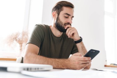 Kafkas düşünen bir adamın otururken cep telefonuyla yazması.