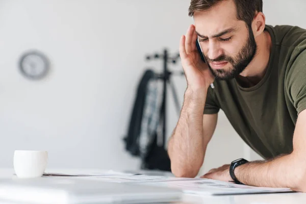 Imagen del hombre caucásico disgustado leyendo documentos y tomando notas — Foto de Stock