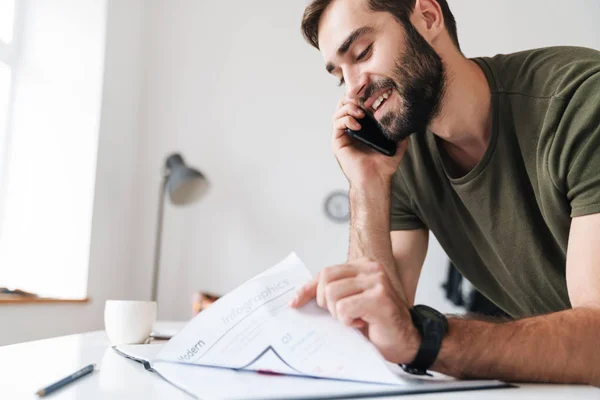 Bild eines zufriedenen kaukasischen Mannes beim Lesen von Dokumenten und beim Telefonieren — Stockfoto