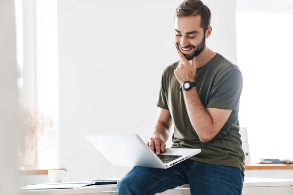 Bild eines gutaussehenden Mannes, der auf seinem Laptop tippt und lächelt — Stockfoto