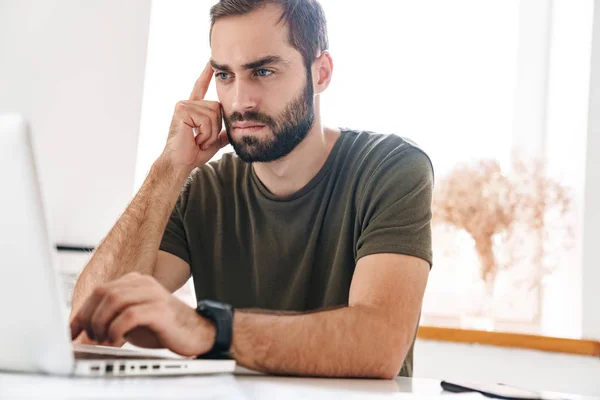 Immagine di bell'uomo concentrato che digita sul computer portatile mentre è seduto — Foto Stock