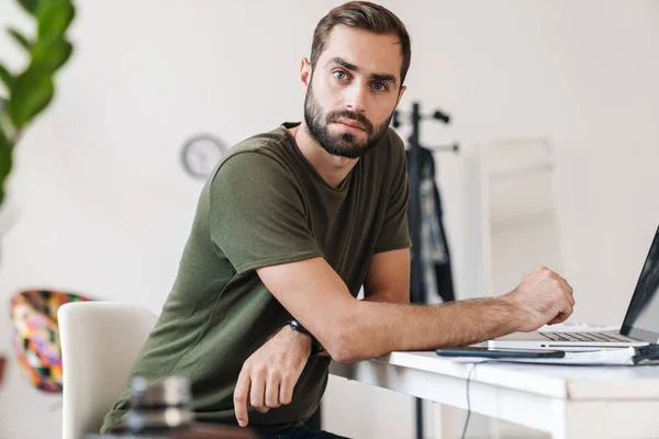 Imagen de un joven caucásico usando un portátil mientras está sentado en el escritorio —  Fotos de Stock