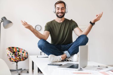 Otururken kulaklıkla müzik dinleyen gülümseyen bir adam görüntüsü