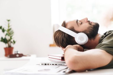 Kulaklıkla müzik dinleyen ve yalan söyleyen genç ve rahat bir adamın görüntüsü