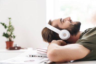 Masada yatarken kulaklıkla müzik dinleyen bir adam görüntüsü