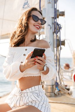 Cep telefonu kullanan neşeli, genç bir kadın..