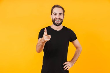 Tişört giyen, gülümseyen ve parmağıyla işaret eden mutlu bir adam resmi.