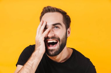 Tişörtlü neşeli bir adamın gülüşü ve yüzüne dokunuşu.