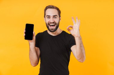 Çekici bir adamın tamam işareti göstermesi ve cep telefonu tutması