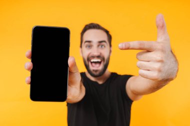 Tişört giyen, gülümseyen ve parmağıyla işaret eden mutlu bir adam resmi.