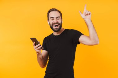 Kulaklıklı çekici bir adamın cep telefonuyla müzik dinlemesi.