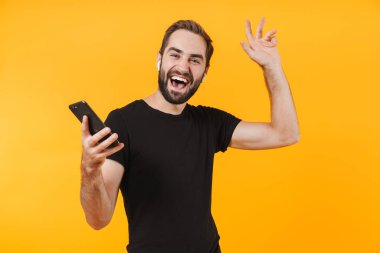 Kulaklıklı yakışıklı bir adamın cep telefonuyla müzik dinlemesi.