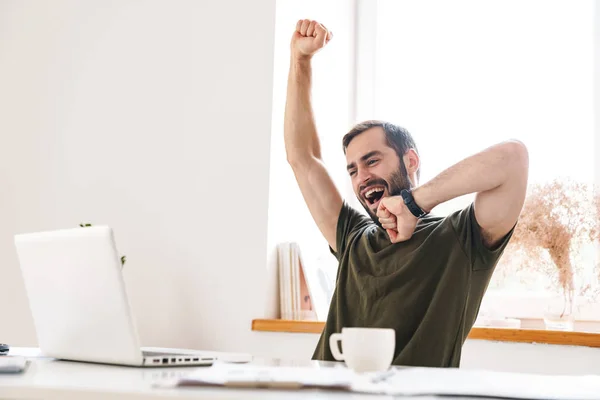 Image of caucasian sleepy man looking at laptop and yawning — 스톡 사진