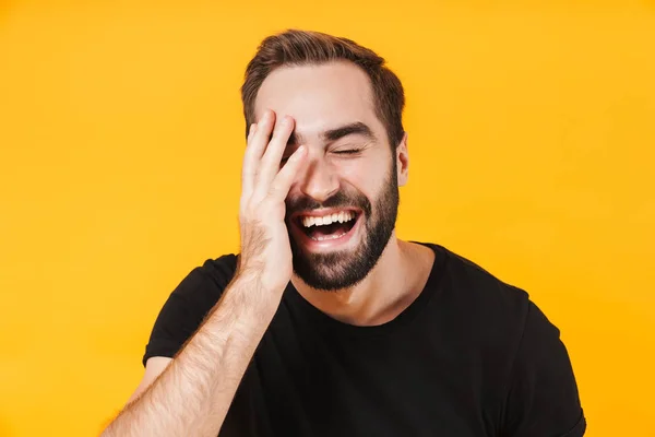 Afbeelding van een ongeschoren man in een t-shirt die lacht en zijn gezicht aanraakt — Stockfoto