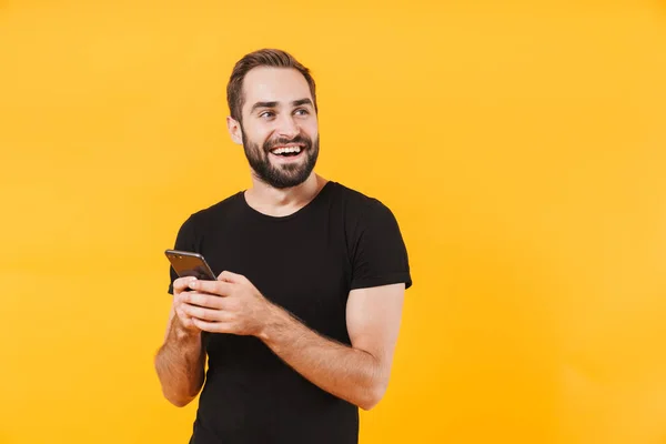 Beeld van een succesvolle man die een t-shirt draagt glimlachend en smar vasthoudend — Stockfoto