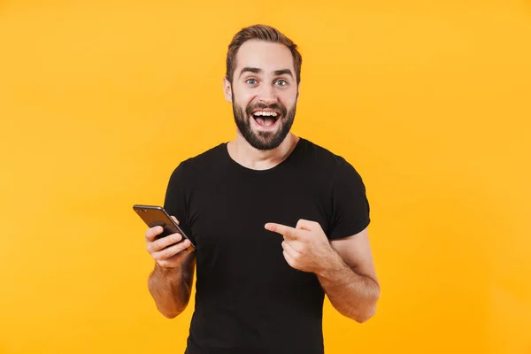 Beeld van een verraste man die een t-shirt draagt lachend en slim vasthoudend — Stockfoto