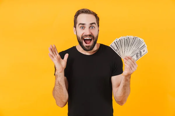 Image of attractive man wearing t-shirt smiling and holding mone — Stock Photo, Image