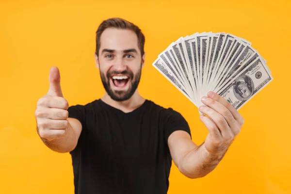 Imagen del hombre sin afeitar vistiendo camiseta sonriendo y sosteniendo el dinero — Foto de Stock