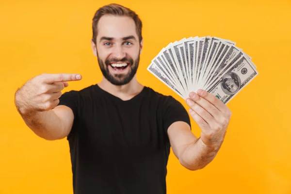 Bild eines positiven Mannes mit T-Shirt, der lächelt und Geld in der Hand hält — Stockfoto