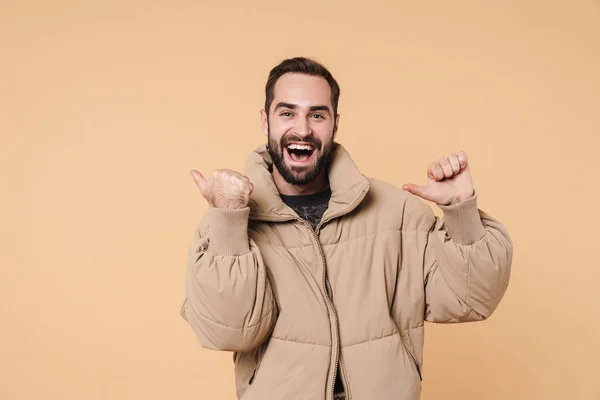 Image of young man in winter jacket smiling and pointing fingers — 스톡 사진