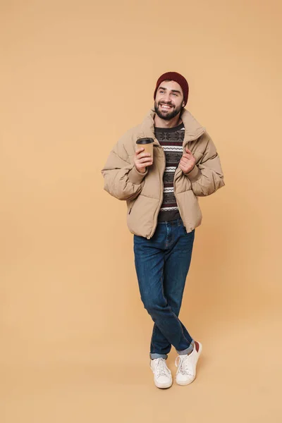 Image of man in winter jacket and hat smiling while holding coff — 스톡 사진