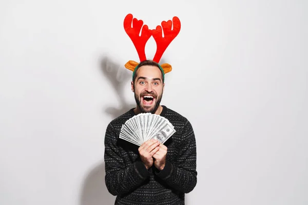 Image of man in Christmas reindeer antlers holding dollar bankno — 스톡 사진