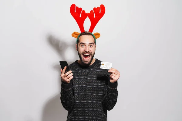 Image of man in Christmas reindeer antlers holding smartphone an — 스톡 사진